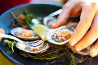 una persona sosteniendo un plato de comida con ostras encima en Appellation Lodi - Wine & Roses Resort and Spa, en Lodi