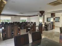 Un comedor con sillas y mesas y una gran sala. en Hotel Varay Express, en Ujjain