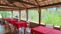 Un comedor con mesas y sillas rojas y árboles. en Suarez Hotel, en Antsiranana