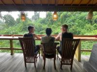 Tres hombres sentados en una mesa mirando por una ventana. en WW Backpackers, en Ubud