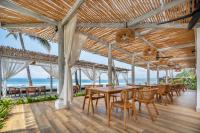 einen Essbereich mit Tischen, Stühlen und Meerblick in der Unterkunft Nirwana Beach & Resort in Candidasa
