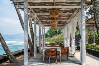 eine hölzerne Pergola mit Tisch und Stühlen am Strand in der Unterkunft Nirwana Beach & Resort in Candidasa
