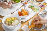 a table with bowls of food and people eating food at Blue Rabbit Hotel in Chanthaburi