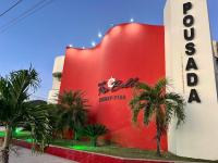 un edificio rojo con palmeras delante en Pousada Piu Bella, en Jequié