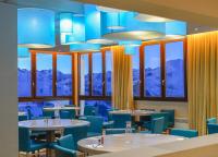 a dining room with tables and blue chairs and windows at Villages Clubs du Soleil - LES 2 ALPES in Les Deux Alpes