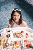 una mujer sentada en una piscina con una mesa de comida en Bantique Hotel, en Da Nang