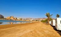 eine unbefestigte Straße mit einem Wohnmobil neben einem Wasserkörper in der Unterkunft Caravan In the Desert in Eilat