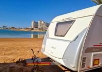 ein Wohnmobil, der an einem Strand neben einem Wasserkörper parkt in der Unterkunft Caravan In the Desert in Eilat