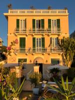 アラッシオにあるHotel Villa Igeaの緑色の窓とバルコニーのある大きな黄色の建物
