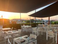 ein Restaurant mit Tischen, weißen Stühlen und einem Sonnenschirm in der Unterkunft Villa Rosy in Torre del Lago Puccini