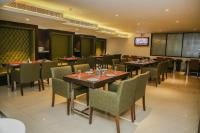 a dining room with tables and chairs and a tv at Citrus Prime Raipur in Raipur