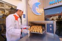 um homem colocando uma bandeja de salsichas no forno em MinaMark Beach Resort for Families and Couples Only em Hurghada