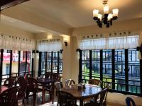 Un restaurante con mesas y sillas y grandes ventanales. en Gracious Lodge, en Shillong