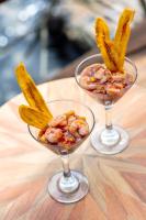 Bahia MaracaiboにあるMonasterio del Vientoの木製のテーブルの上に食べ物が入ったワイングラスが2つ