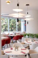 a dining room with tables and chairs and chandeliers at Ramada by Wyndham Bucharest Otopeni Airport in Otopeni