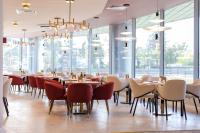 a restaurant with tables and chairs and windows at Ramada by Wyndham Bucharest Otopeni Airport in Otopeni