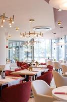 a restaurant with tables and chairs and a chandelier at Ramada by Wyndham Bucharest Otopeni Airport in Otopeni