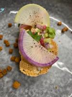 a sandwich with a slice of onion and vegetables at Hotel la Turra in Termignon