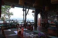 Un restaurante con mesas y sillas y un gran ventanal. en Himalayan Hobbit House, en Almora