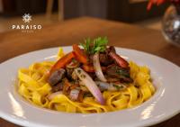 a plate of pasta with meat and vegetables on a table at Hoteles Paraiso PIURA in Piura