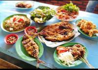 una tavola ricoperta di piatti di cibo su piatti di Krui ocean cottage a Krui