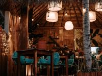 Un restaurante con sillas azules, una mesa y luces. en Khaban Bacalar Hotel Boutique, en Bacalar