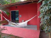 a hammock on the porch of a red house at Pousada ZEN Cumuruxatiba in Cumuruxatiba