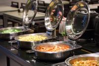 four pans of food on a counter in a kitchen at Just Enjoy Business Hotel in Tainan