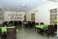 a dining room with green tables and chairs at Nilambag Palace Hotel in Bhavnagar