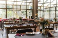 une salle à manger avec tables, chaises et fenêtres dans l'établissement Pastoral Lodge at the Sanctuary of the Divine Mercy, à Cracovie