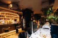 a restaurant with tables and a bar with people preparing food at Ridge Apartments in Chernivtsi