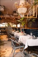 a restaurant with white tables and chairs and a chandelier at Ridge Apartments in Chernivtsi