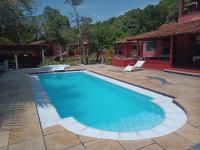 a swimming pool with a chair and a house at Pousada ZEN Cumuruxatiba in Cumuruxatiba
