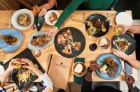 Un grupo de personas sentadas alrededor de una mesa comiendo comida en Hotel Olivewood, en East London