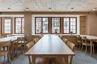 Una gran sala con mesas, sillas y ventanas. en POORT A POORT Dorfhotel, en Grengiols