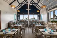 ジキル島にあるホリデイ イン リゾート ジキル アイランドの木製のテーブルと椅子、大きな窓のあるレストラン