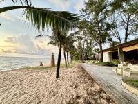 a beach with palm trees and a building and the ocean at Bellevue west Phu Quoc 4BR beachfront Villa with private swimming pool in Phu Quoc