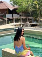 a woman in a dress sitting next to a swimming pool at JJ&amp;J Garden in Pai
