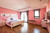 a bedroom with pink walls and a white bed at 好趣淘休閒民宿 電梯 車位預約制 in Hualien City