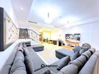 ein Wohnzimmer mit einer großen Couch in der Mitte in der Unterkunft Stylish 3-bedroom plus Maid room - Villa in JVC - Dubai in Dubai