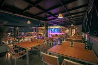 a restaurant with wooden tables and chairs and purple lighting at Hotel M Pro Palace Mysore - 12 Minutes to Mysore Palace in Mysore