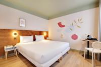 Un dormitorio con una gran cama blanca y una mesa. en Hôtel Cocoon, en Saint-Ouen