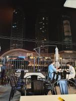 Twee mannen zitten 's nachts aan tafels op een balkon. bij Elysium Luxury 1Bed Apartment! Opposite to Centaurus Mall in Islamabad