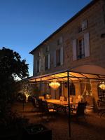 una mesa y sillas bajo una sombrilla frente a un edificio en Guest house with charm, Le figuier, en Vignonet