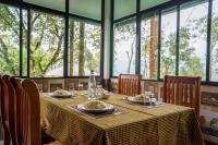 Un comedor con mesa y sillas y ventanas. en Swag Vista Resort, en Anachal