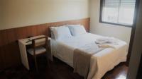 Un dormitorio con una cama, una mesa y una silla. en Hotel Mazzuco, en Araranguá