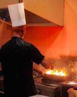 um chef a cozinhar comida numa panela num fogão em Royal Crown Residency Hotel em Talawatugoda