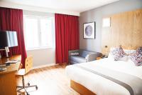 a hotel room with a bed and a chair at Ramada by Wyndham Belfast in Belfast