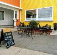 MarysvilleにあるHotel Wolfe Islandの黄色い建物の前にあるテーブルと椅子のあるレストラン