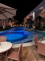 een zwembad 's nachts met tafels en stoelen bij GUARAJUBA Porto Smeralda Flat in Guarajuba